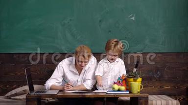 上学。 教室里有家长的小学生。 母亲帮助儿子写功课。 快乐老师帮助小学生
